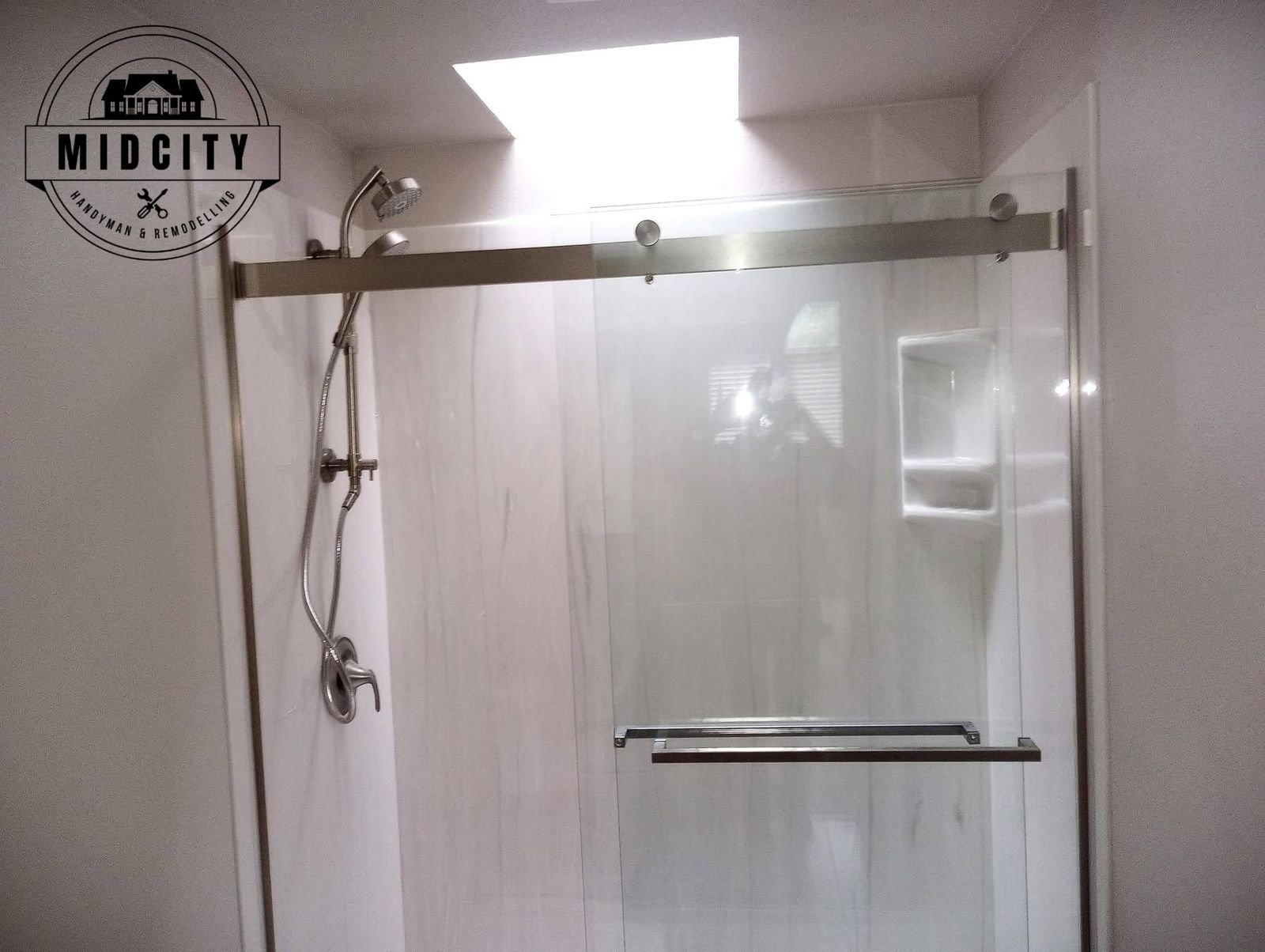 Glass slider shower with skylight and marble look panels