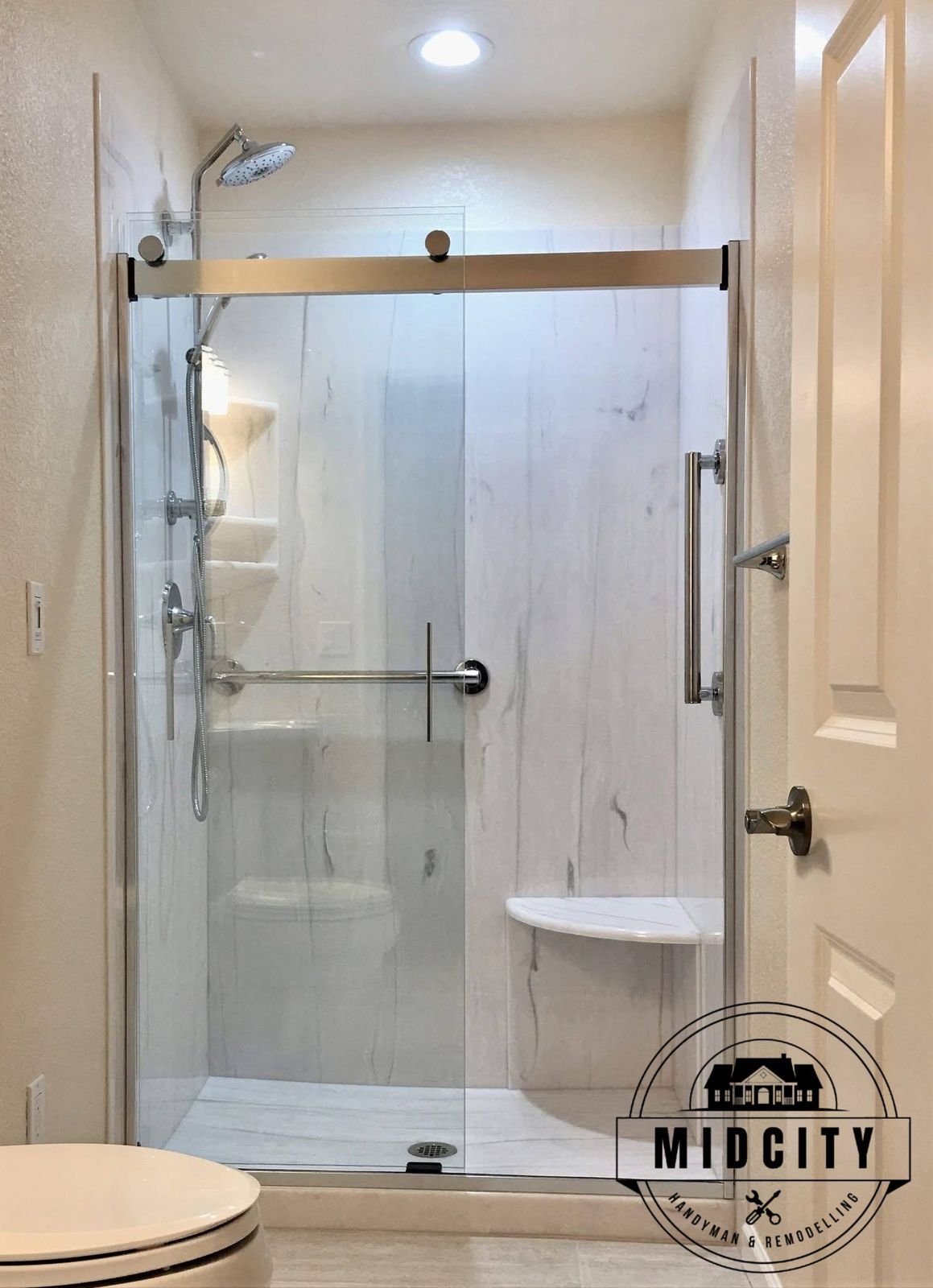 Walk-in shower with sliding glass door, grab bar and corner bench